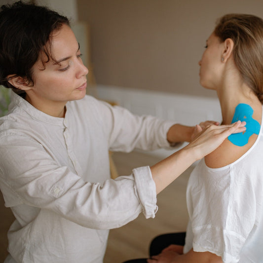 Eine Physiotherapeutin behandelt die Schulter einer Patientin